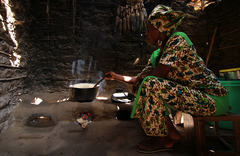 African woman in a hut, cooking in a cookstove