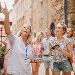 Group of people standing in a street and listening to a tour guide in Volterra, Italy. 