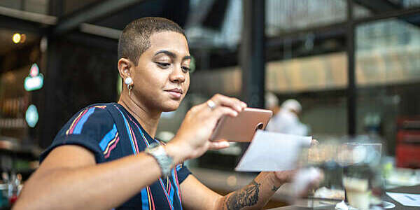 Young woman in a café busy depositing a check by smartphone.
