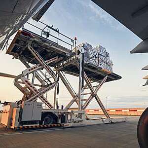 Full view of giant scissor lift loading cargo onto an aircraft at the airport.