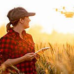 Woman farmer controls drone with a tablet. Smart farming and agriculture