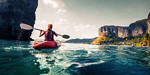 Lady paddling the kayak in the calm tropical bay